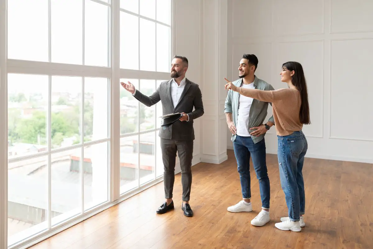 Agent immobilier montrant un appartement lumineux à un jeune couple intéressé.